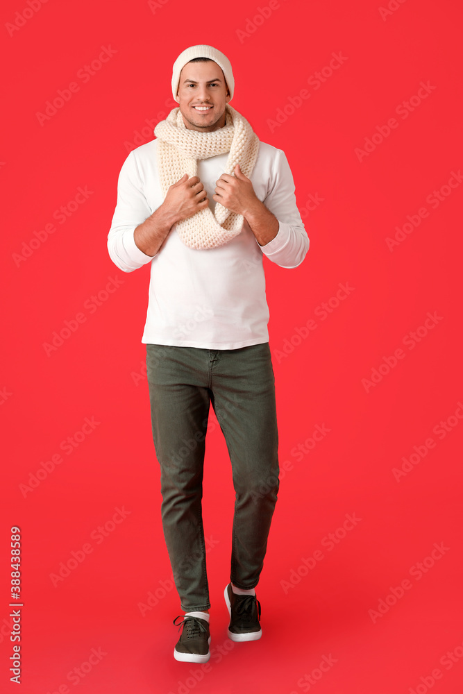 Handsome young man in winter clothes on color background