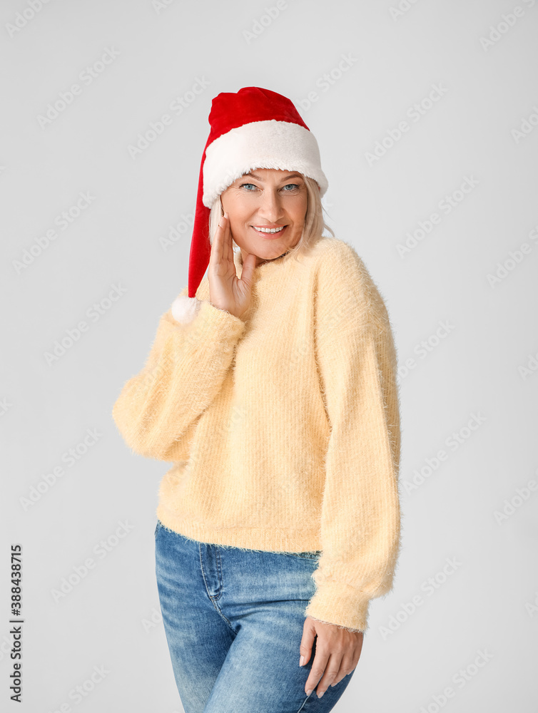 Mature woman in Santa hat on light background