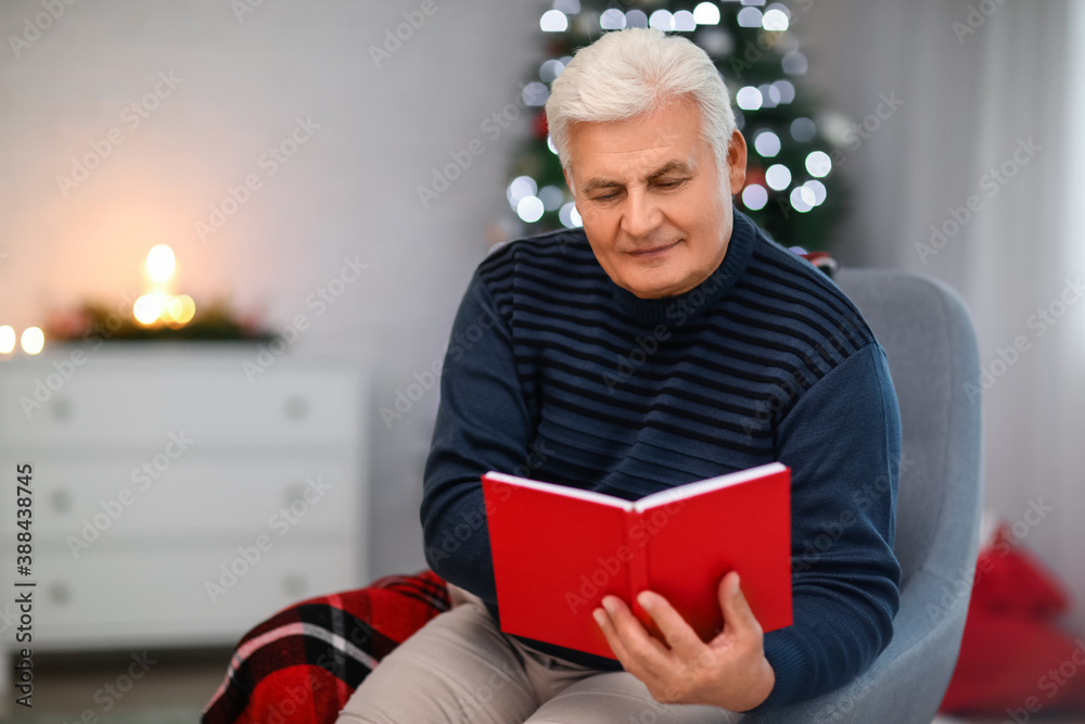 Mature man reading book at home on Christmas eve