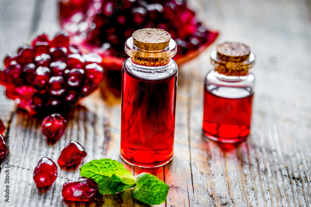 sliced pomegranate and extract in glass on wooden background