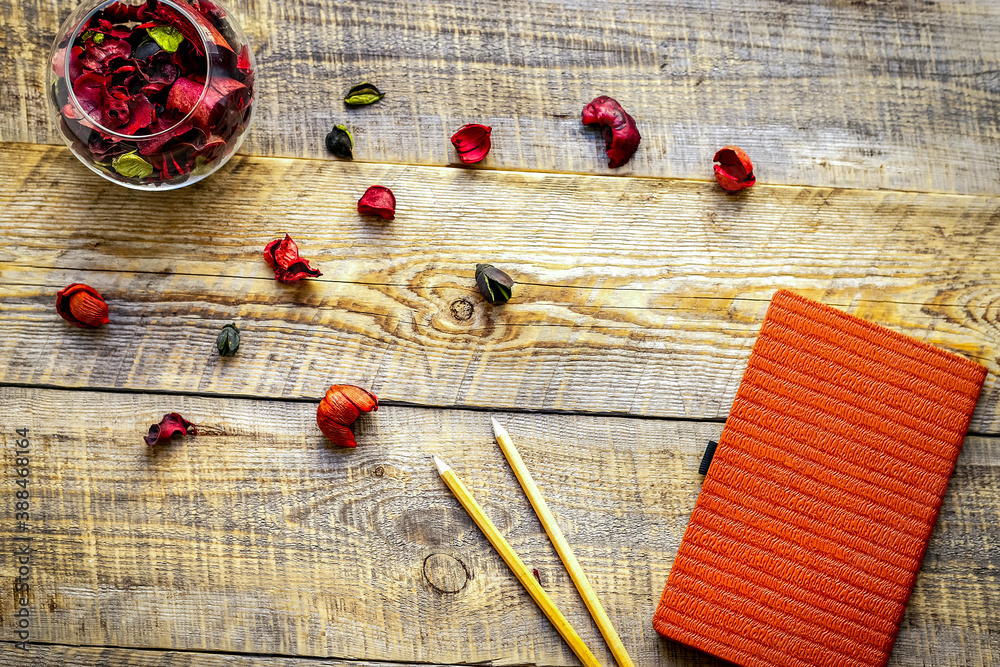 orange notebook with flower sachets on wooden table