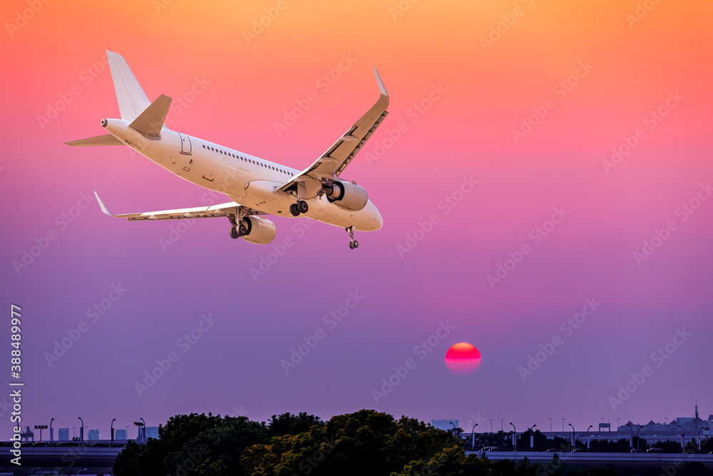 Commercial airplane flying above clouds in sunset.