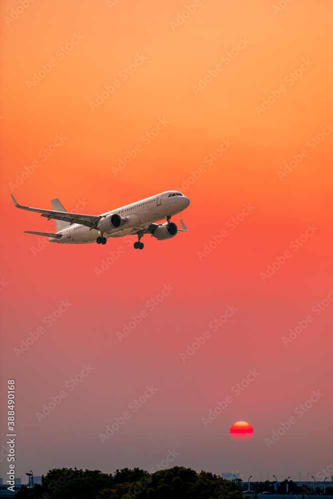 Commercial airplane flying above clouds in sunset.