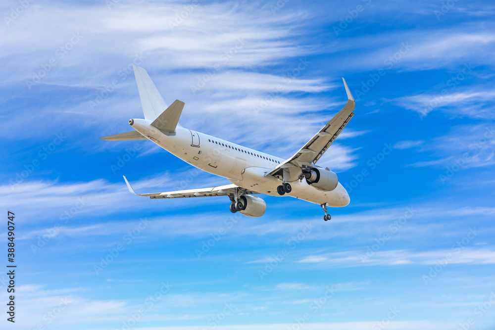 Commercial airplane flying above blue sky and white clouds.