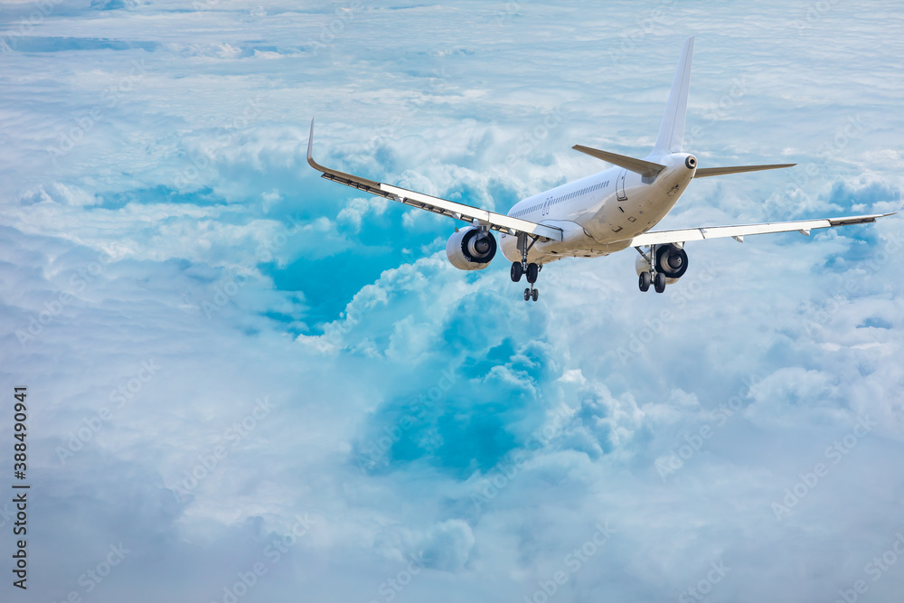 Commercial airplane flying above blue sky and white clouds.