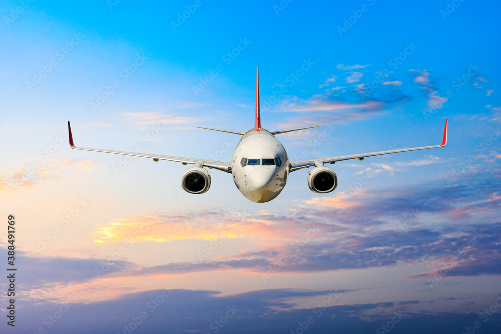 Commercial airplane flying above clouds in colorful sunset.Travel,holidays and business concept.