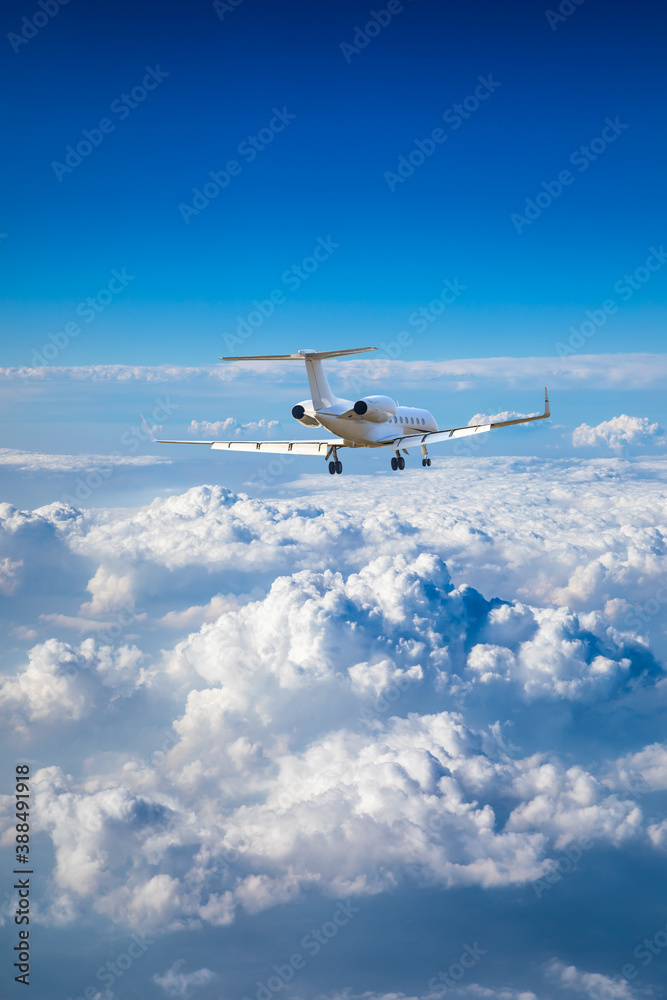 Commercial airplane flying above blue sky and white clouds.