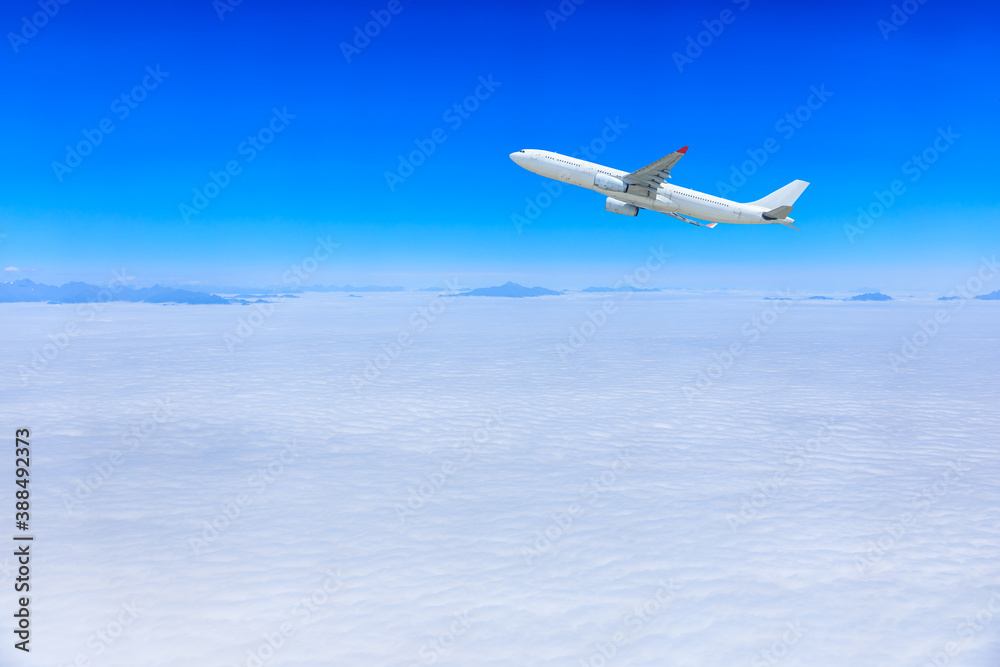 Commercial airplane flying above blue sky and white clouds.