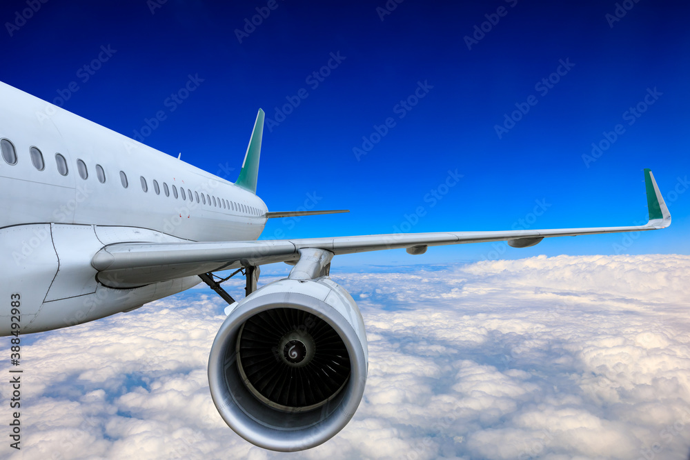 Commercial airplane flying above blue sky and white clouds.