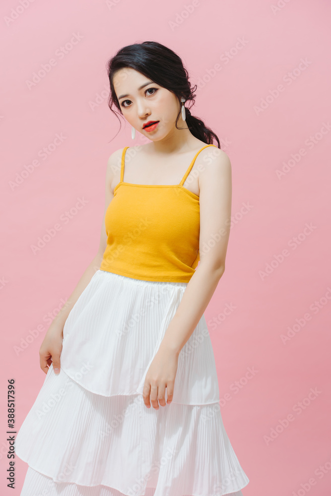 Full length fashion girl in yellow top and white long skirt posing on pink background