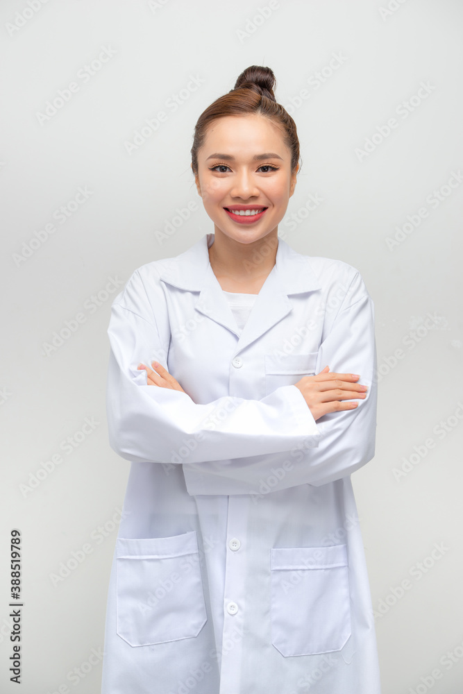 Smiling female doctor in lab coat with arms crossed against white background