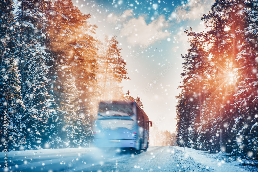 Bus on asphalt road in beautiful winter day at countryside in snowfall