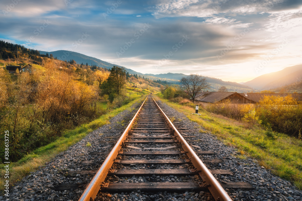 Railroad in mountains at sunset in autumn. Beautiful industrial landscape with railway station, oran