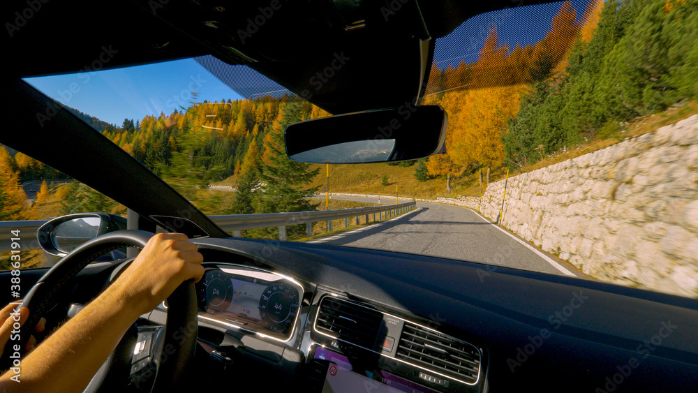 CLOSE UP: Young man having fun driving fast along a scenic route in Dolomites.