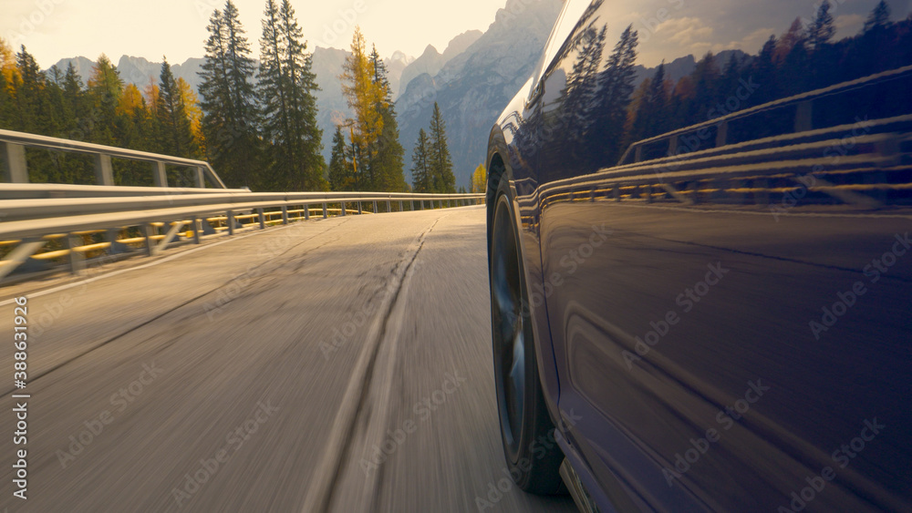 CLOSE UP: Brand new blue car speeds down scenic switchback road in Tre Cime