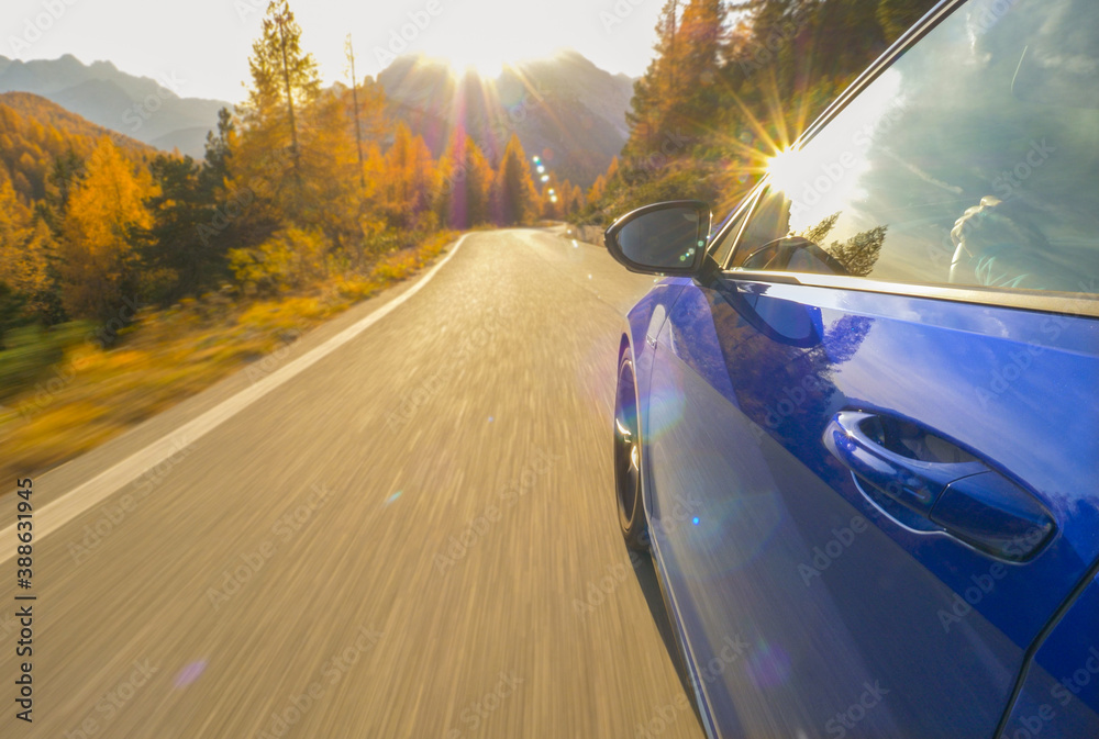 CLOSE UP: Idyllic view of sunlit Dolomites as sportscar drives down scenic road.