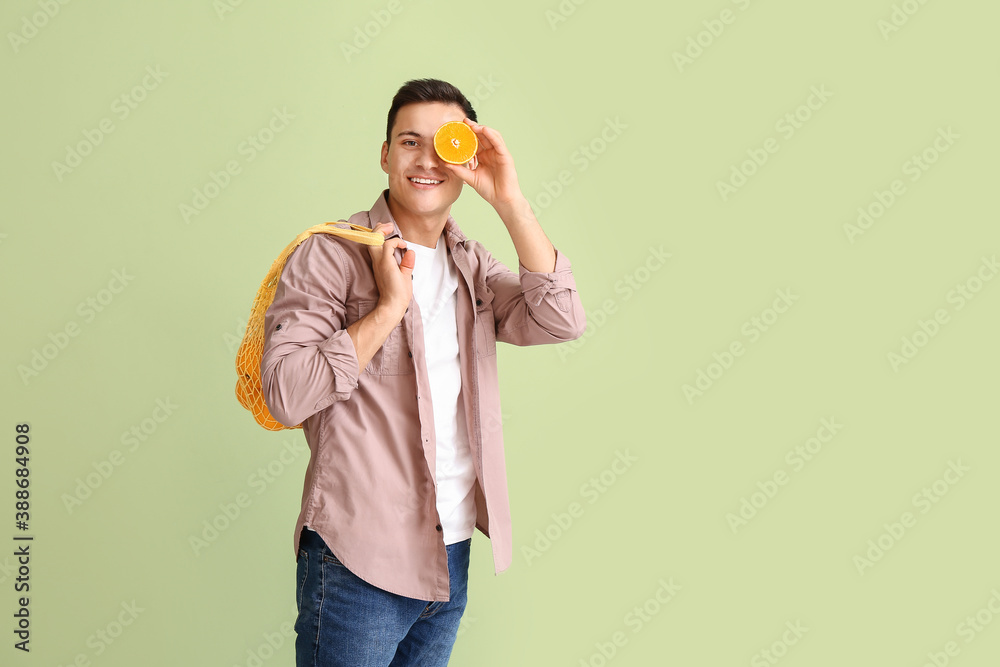 Handsome man with ripe oranges on color background