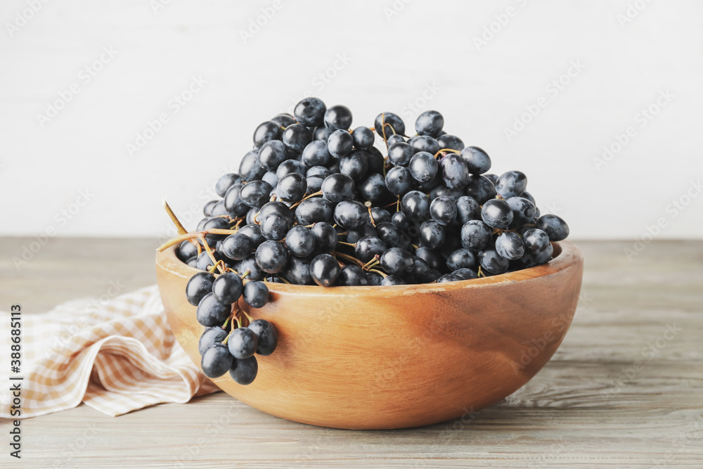 Bowl with sweet ripe grapes on table