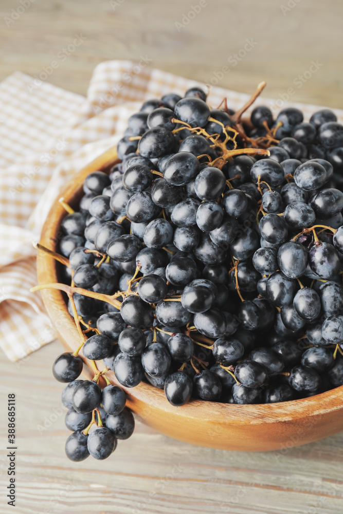 Bowl with sweet ripe grapes on table