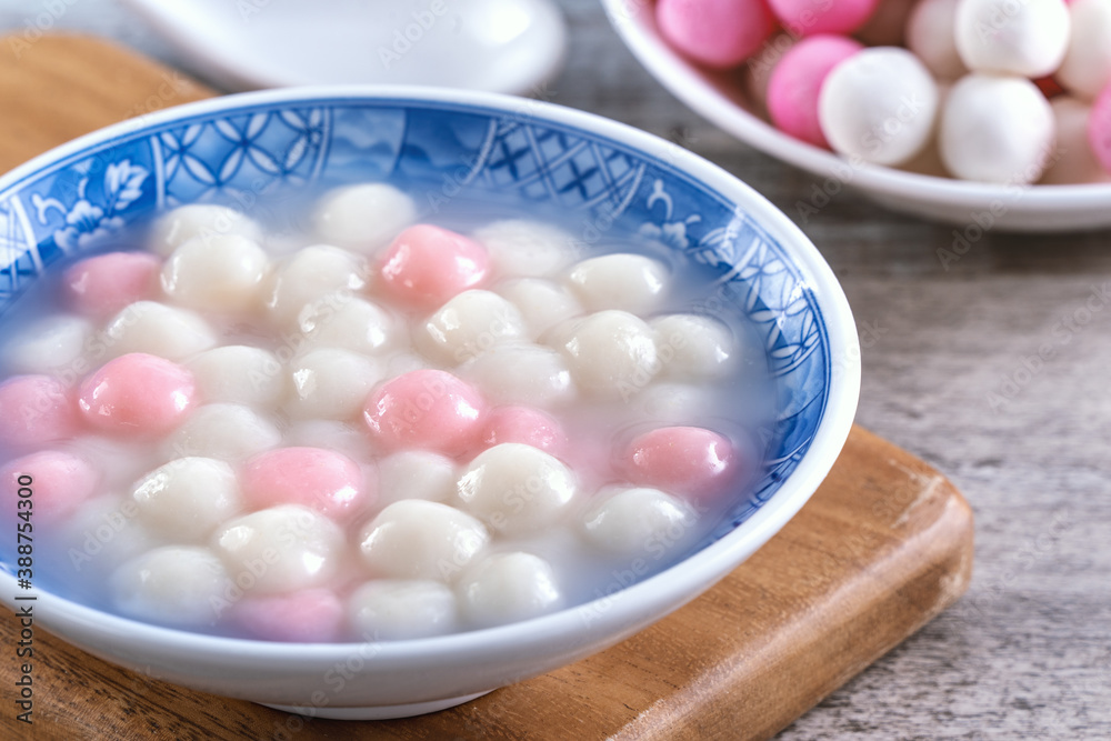 Close up of red and white tangyuan in blue bowl on wooden background for Winter solstice.