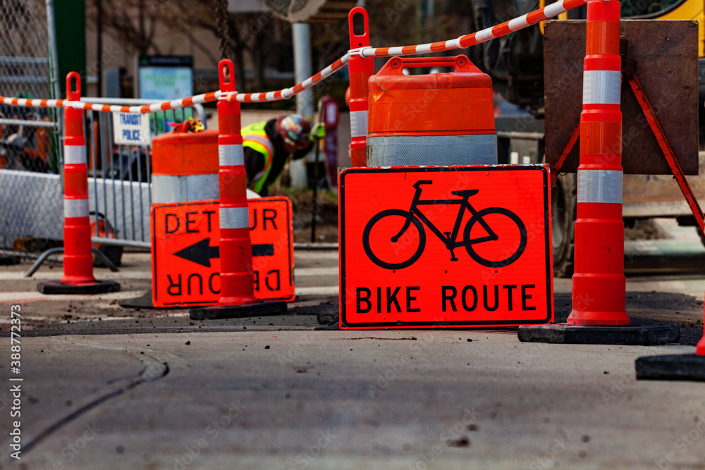 Orange street sign showing bike route detour during outdoor road construction works