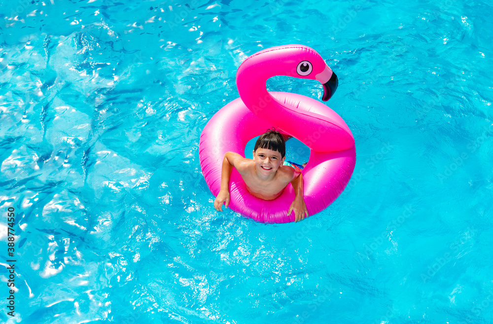 View from above of happy little boy swim on inflatable flamingo ring buoy