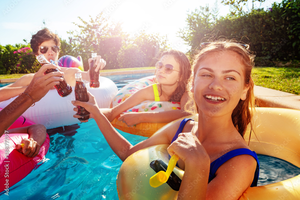 Teenage girl blow noisemaker party in the swimming pool with friends laugh and celebrate