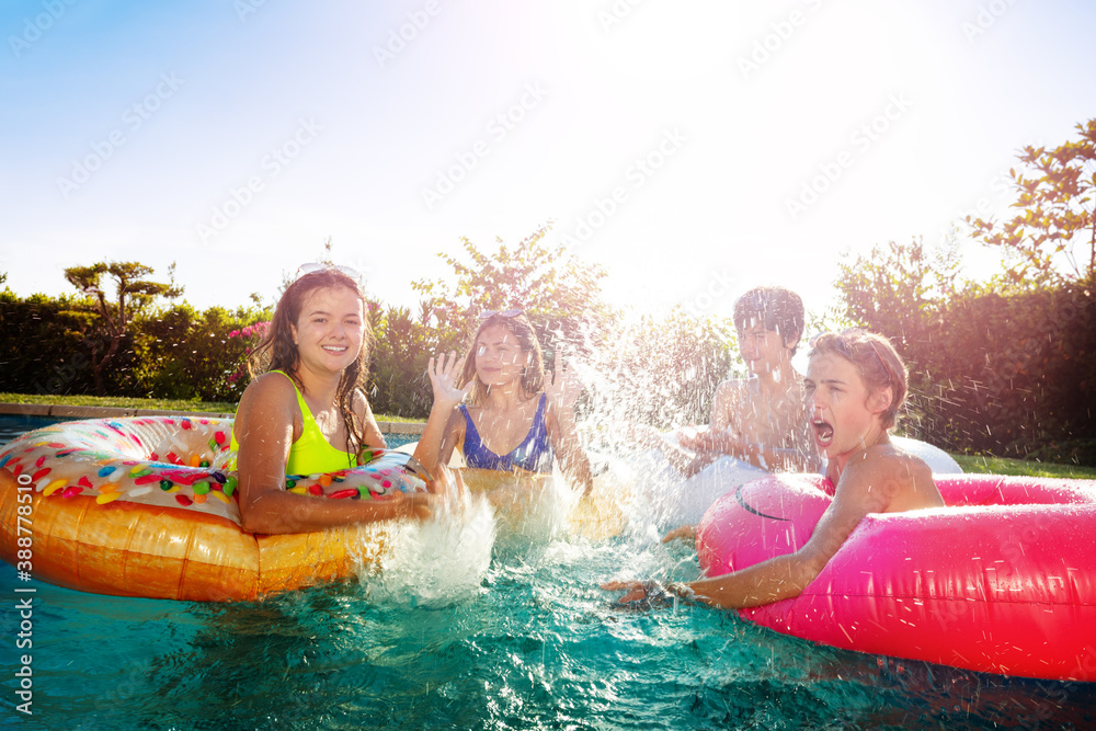 Many children friends with inflatable rings splash in swimming pool playing together having fun