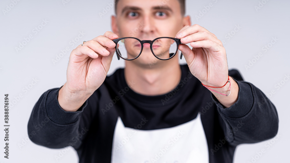 Stylish glasses with black rim in a man`s hands. Studio shot on a white background. Close-up.