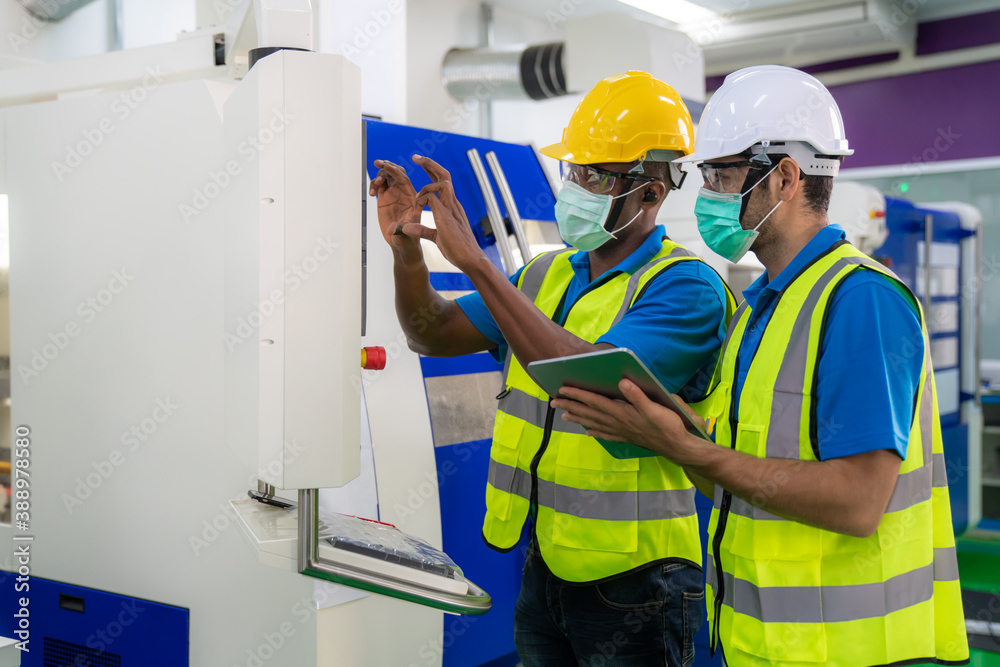 Asian industrial engineers and worker in hard hats discuss product line while using digital tablet i