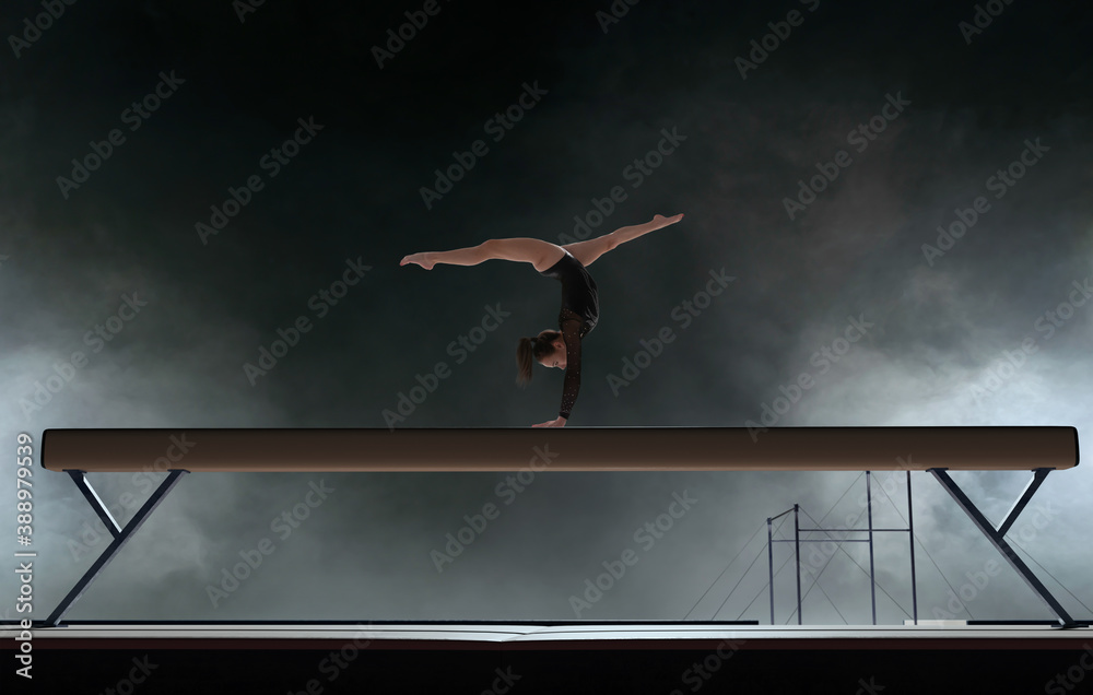 Female gymnast doing a complicated trick in a professional arena.