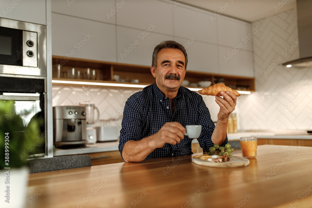 Eating croissant in his kitchen.