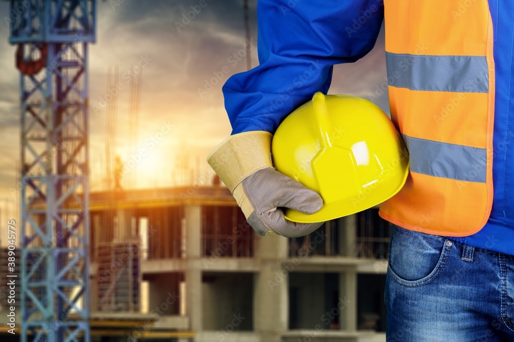 Worker man with helmet in hands on background