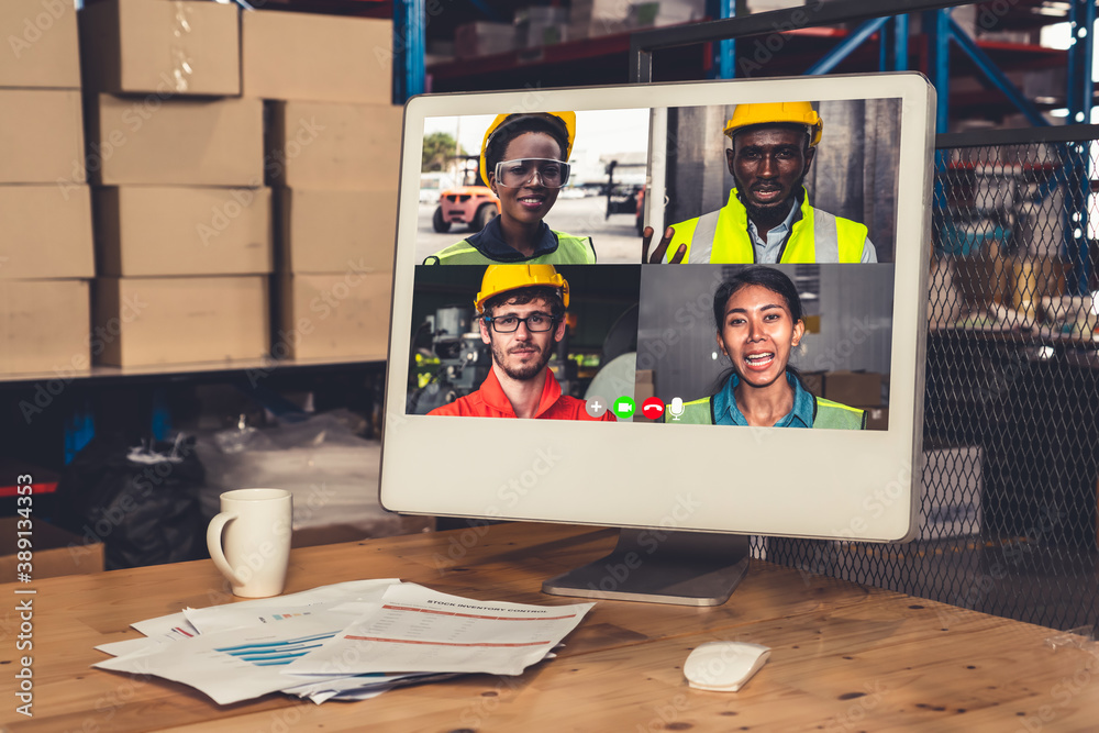 Warehouse staff talking on video call at computer screen in storage warehouse . Online software tech