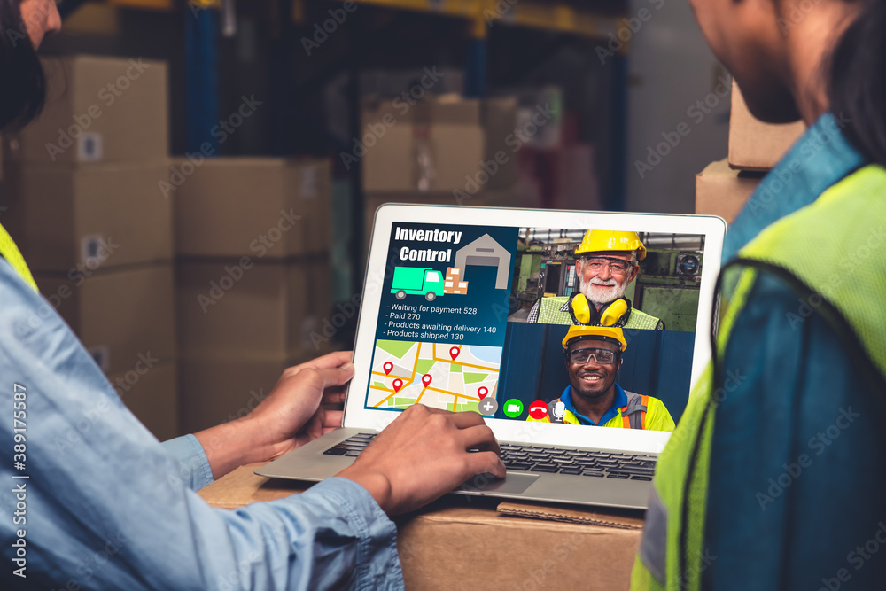 Warehouse staff talking on video call at computer screen in storage warehouse . Online software tech