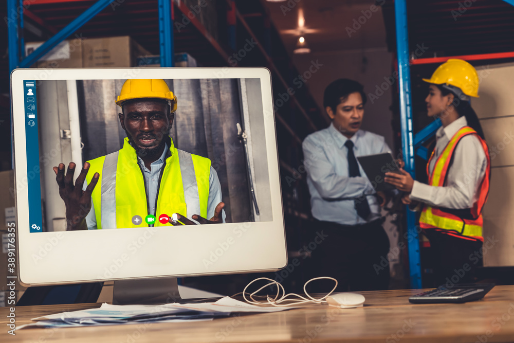 Warehouse staff talking on video call at computer screen in storage warehouse . Online software tech