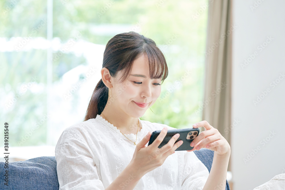 リビングでスマートフォンを使う女性