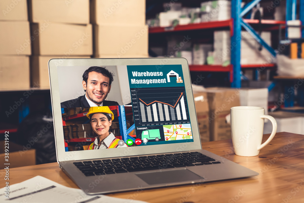 Warehouse staff talking on video call at computer screen in storage warehouse . Online software tech