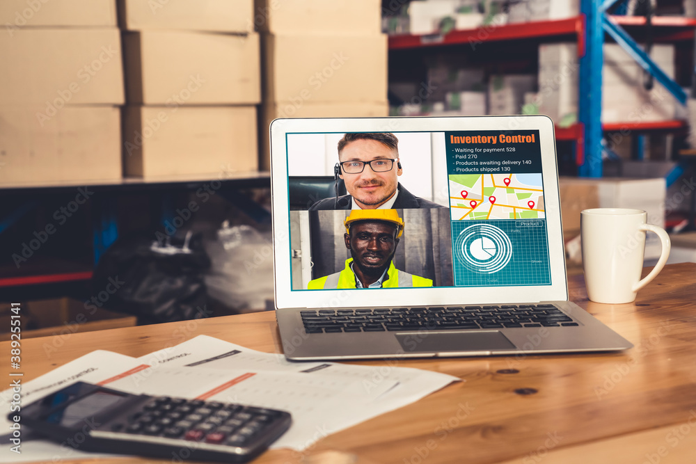 Warehouse staff talking on video call at computer screen in storage warehouse . Online software tech