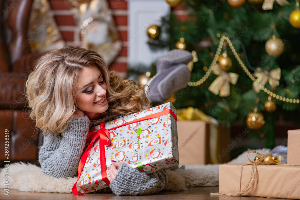 Portrait of a beautiful woman near the Christmas tree. lady unpackages presents. Selective photo.