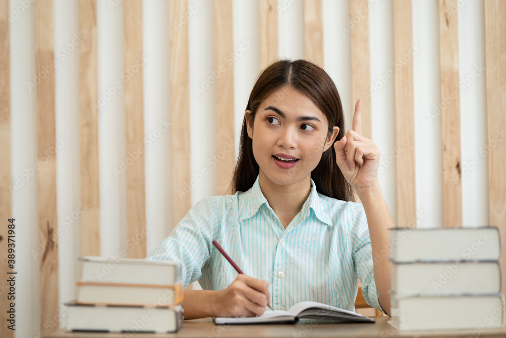 Happy young Asian business woman thinking dreaming has many ideas while working in office