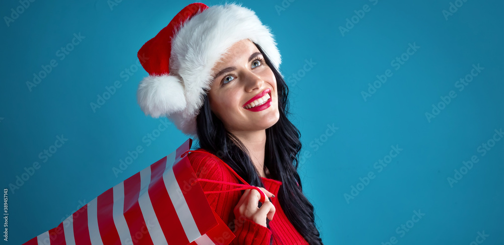 Young woman with santa hat holding a shopping bag on a dark blue background