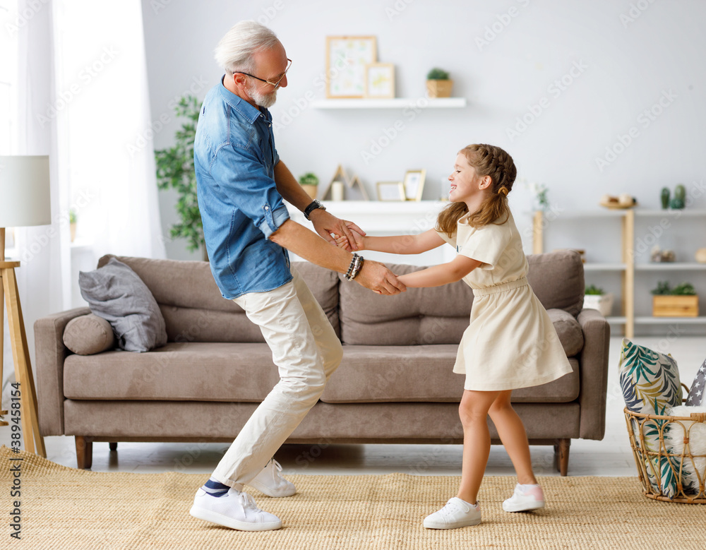 Grandfather dancing with granddaughter at home.