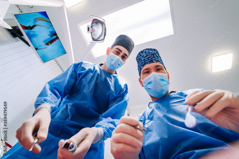 Dentists hold specific medical instruments for examining patient. View from patient`s eyes. Photo fr