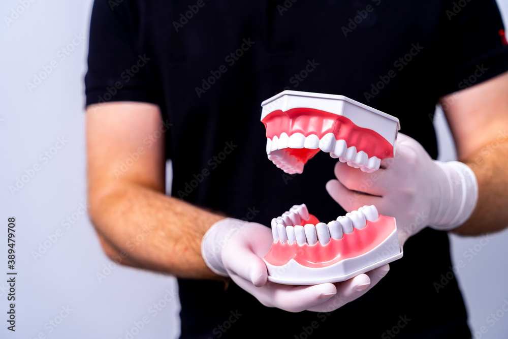 Doctor shows on a plastic jaw sample or model different methods of teeth treatment. Modern dental cl