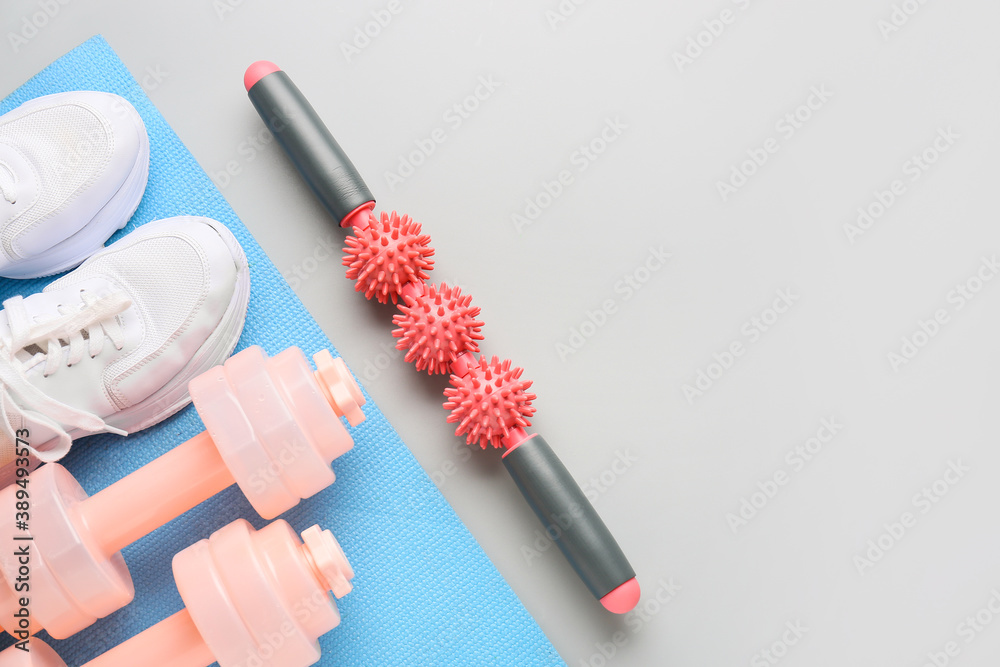 Body roller with shoes and dumbbells on grey background