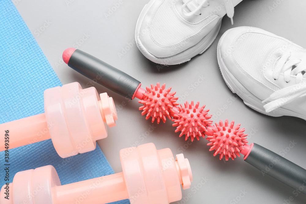 Body roller with shoes and dumbbells on grey background