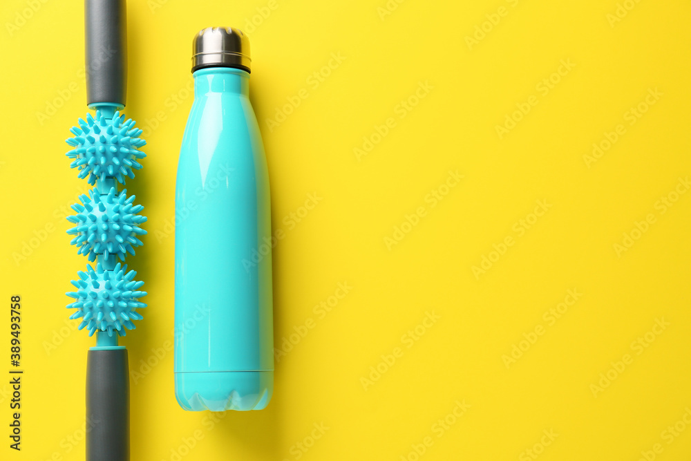 Body roller with bottle of water on color background