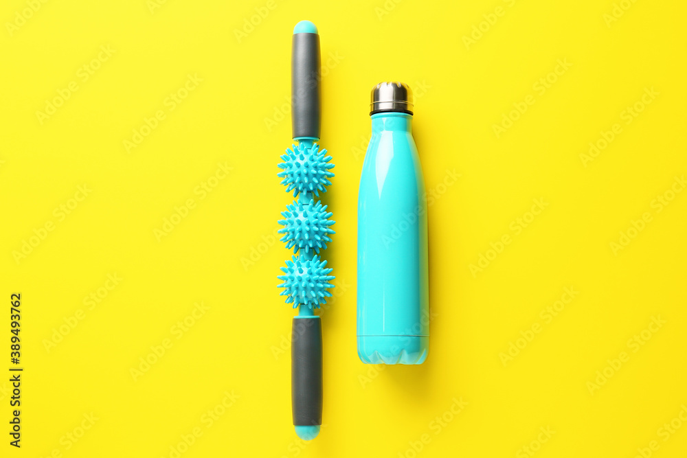 Body roller with bottle of water on color background