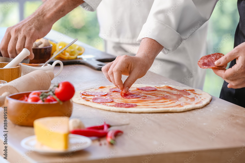 Chef making tasty pizza in kitchen, closeup